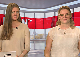 Das Bild ist ein Screenshot aus der Plan-TV-Episode und zeigt die Studierenden Celina und Laura, die diese Plan-TV-Ausgabe moderiert haben.